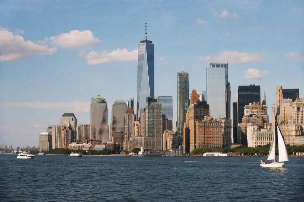 Daylight view of the Lower Manhattan skyline from the water, buildings sharp and detailed under a bright sky with the harbor in the foreground