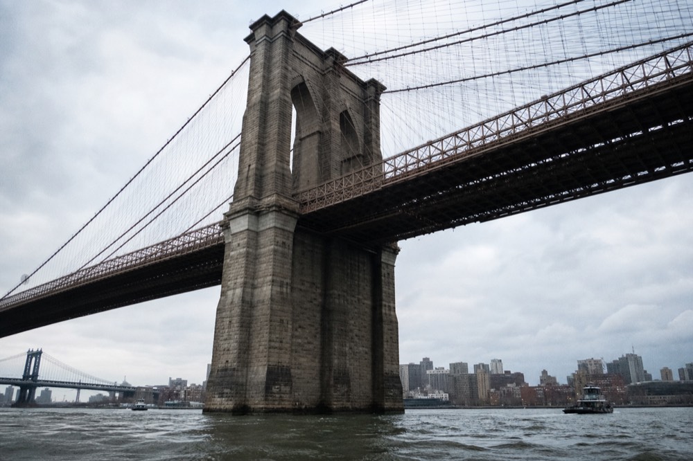 Looking up at the stone towers and fanned cables of a large suspension bridge from directly below on the water