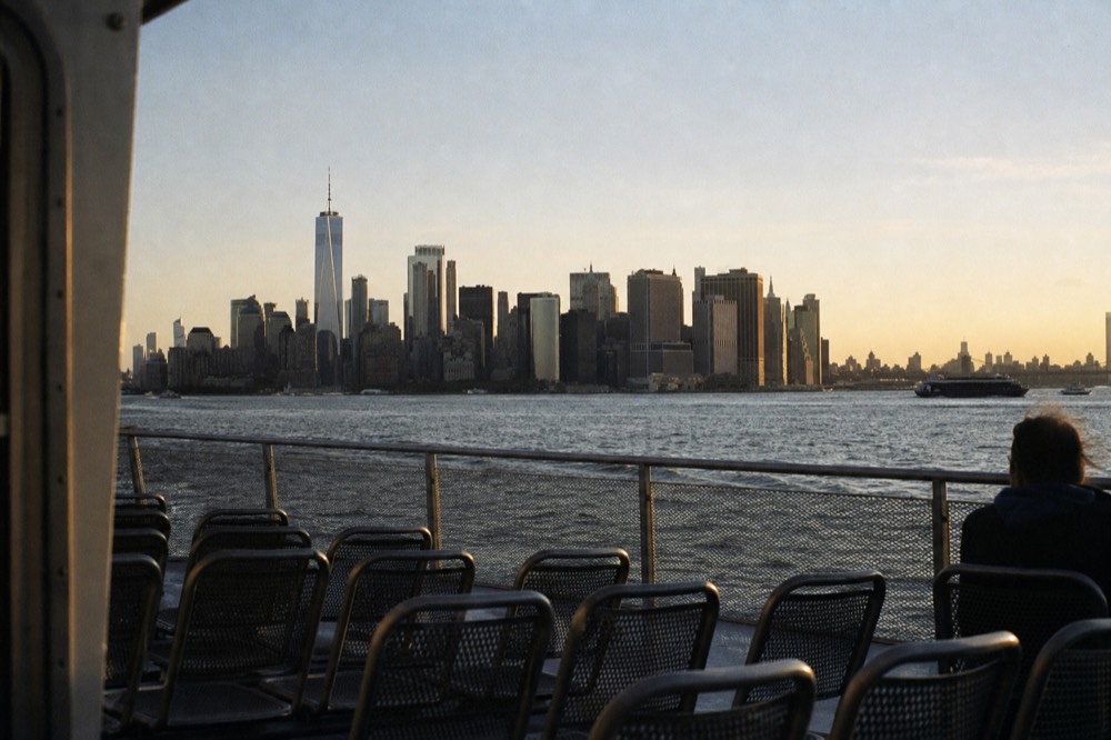 Open upper deck of an excursion boat with empty chairs and the full Manhattan skyline stretching along the horizon behind